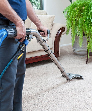 Professional cleaner vacuuming office carpet with commercial cleaning equipment